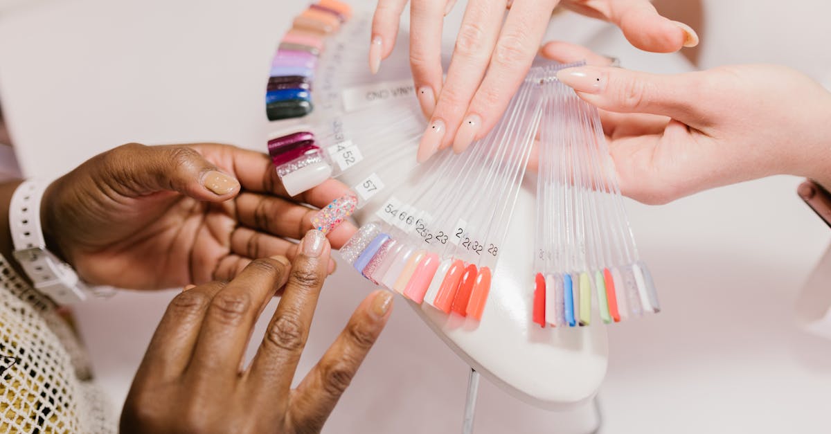 Close-up of hands choosing from a vibrant nail polish sample palette in a salon setting.