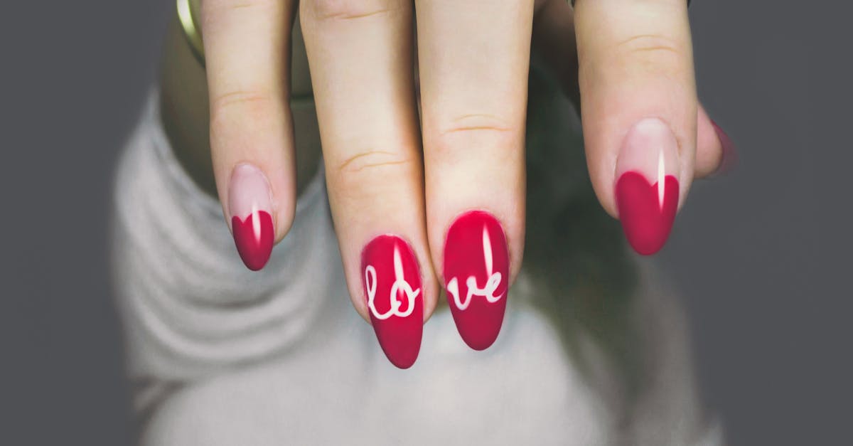Vibrant red nails with 'love' art on a woman's hand, showcasing elegant style and design.